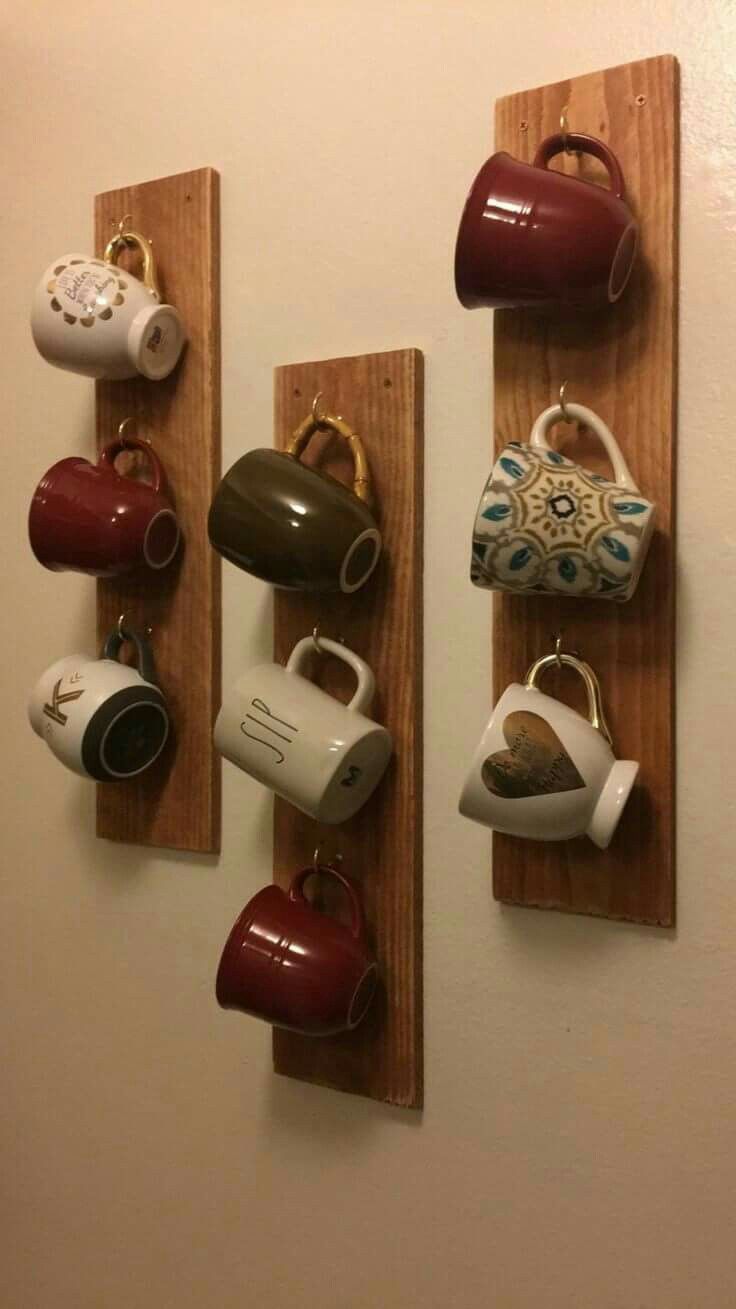 coffee cups and mugs are hanging on the wall with wooden pegs to hold them