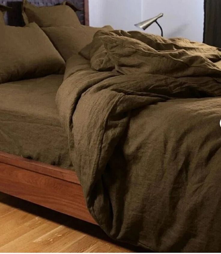 an unmade bed with brown sheets and pillows