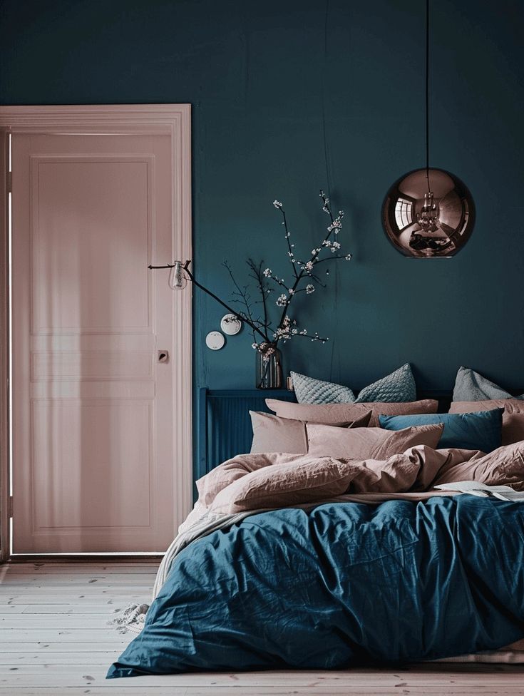 a bedroom with teal walls and blue bedding in the foreground is an open door