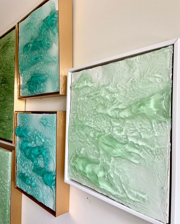 three paintings are hanging on the wall with green and blue paint in them, one is gold