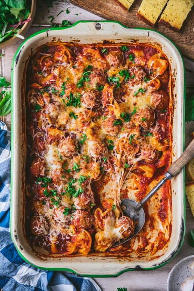 a casserole dish with meat, cheese and parmesan bread on the side