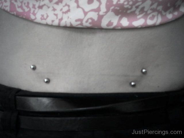 a woman's stomach with three piercings on it and her belly in the background