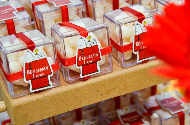 several small containers with marshmallows in them on a wooden shelf next to a red flower