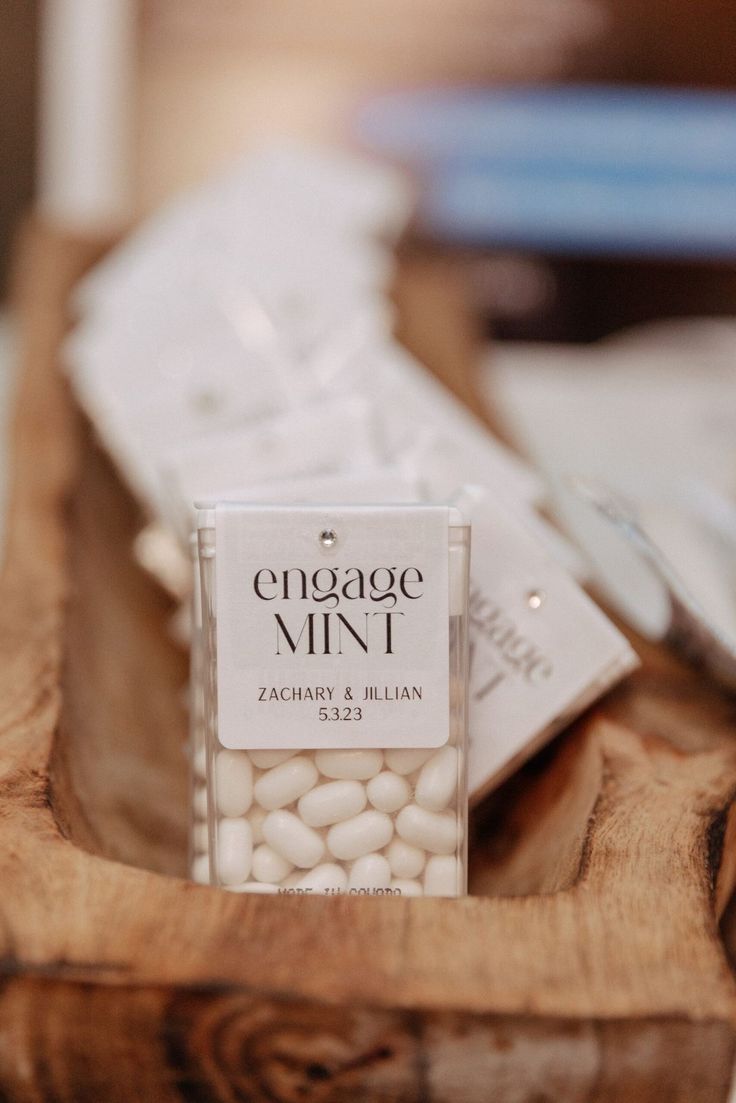 a wooden tray topped with lots of white candies next to a bottle of wine