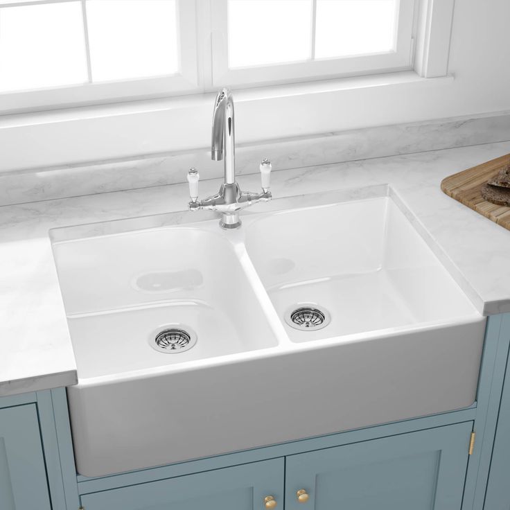 a kitchen sink with two faucets in the middle and blue cabinets on either side