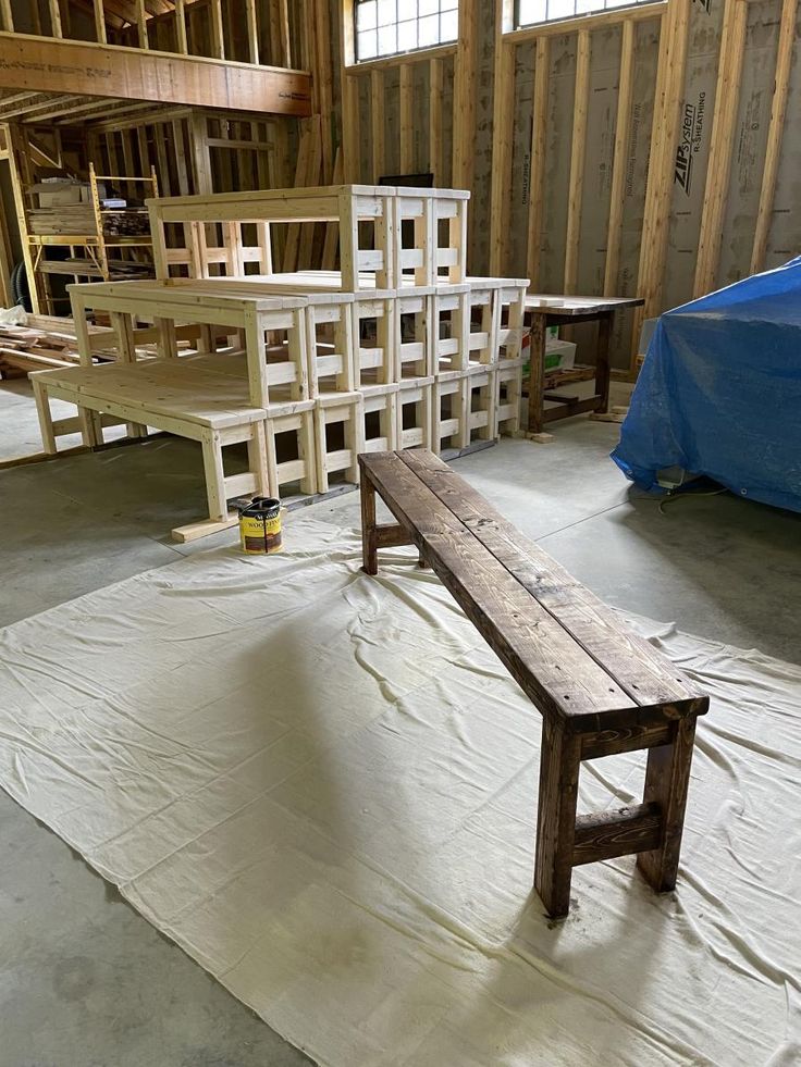 a wooden bench sitting on top of a tarp in a room filled with construction materials