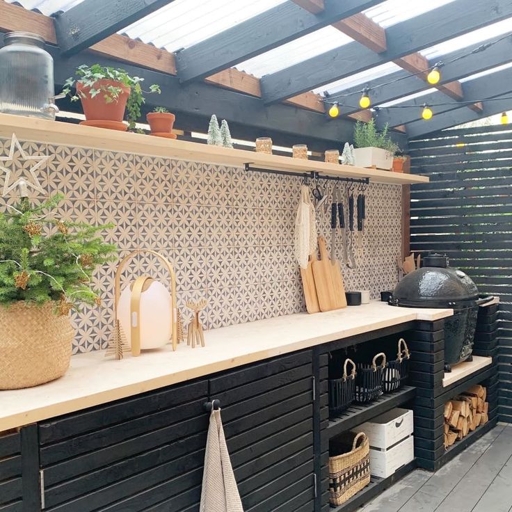 an outdoor kitchen with potted plants and pots on the counter top, along with other utensils