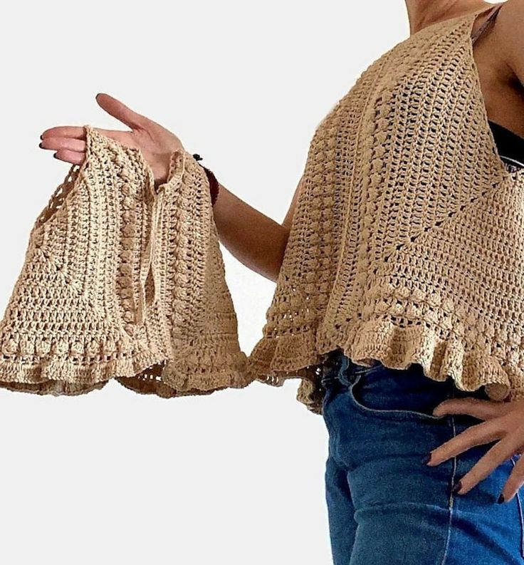 a woman holding two crocheted purses in one hand and pointing at the other