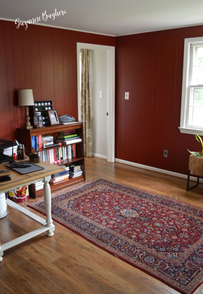 a living room with red walls and wooden flooring has a rug on the floor