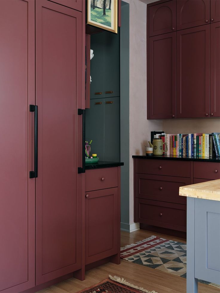 a kitchen with red cabinets and an area rug on the floor in front of it