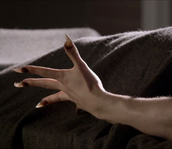 a person's hand reaching for something on a bed with their left arm stretched out