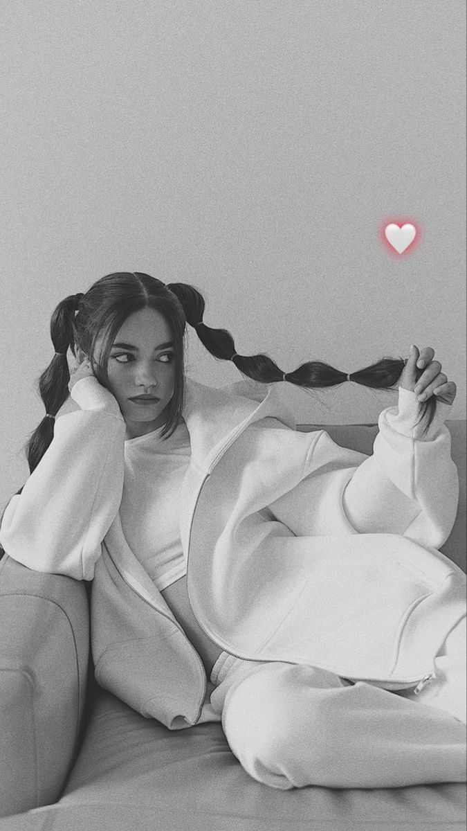 a black and white photo of a woman sitting on a couch holding a hair dryer