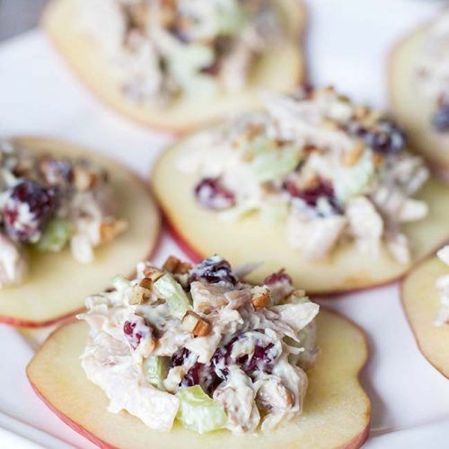 several small appetizers are arranged on a white platter with fruit and nuts