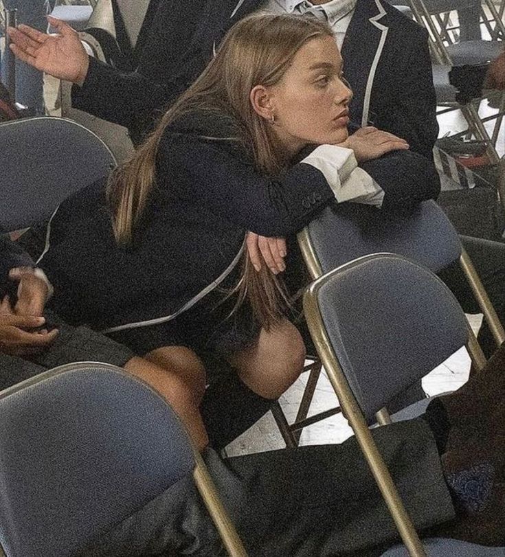 a woman sitting in a row of chairs with her arms crossed