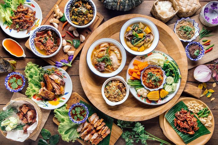 an overhead view of several plates of food on a wooden table with chopsticks