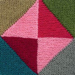 a close up view of a knitted blanket with different colors and shapes on it