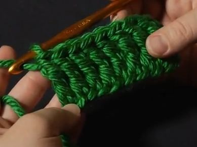 someone crocheting the ends of a green piece of yarn