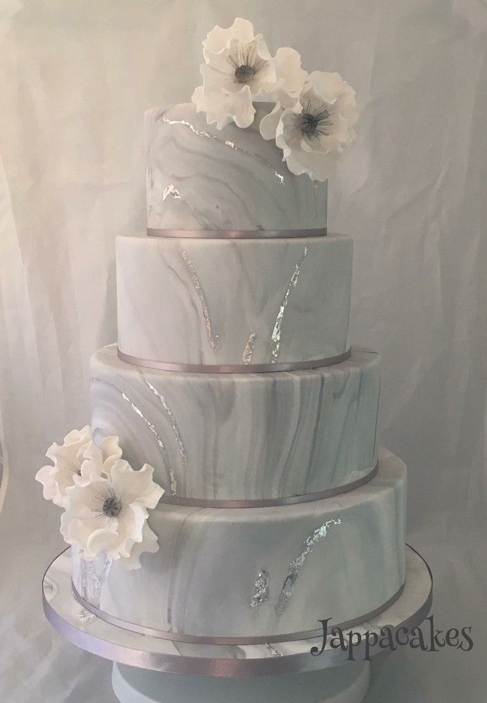 a three tiered marble cake with white flowers on the top and bottom, sitting on a table