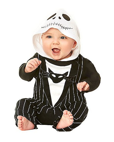 a baby wearing a panda hat and striped suit sitting on the ground with his hands in his pockets