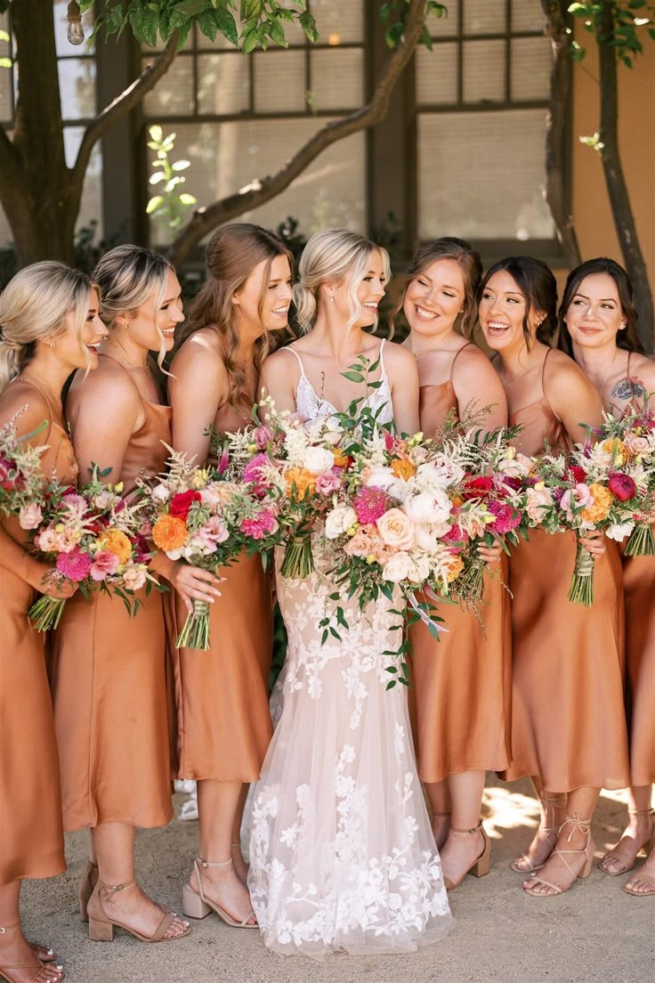 a group of women standing next to each other with bouquets in their hands and smiling at the camera