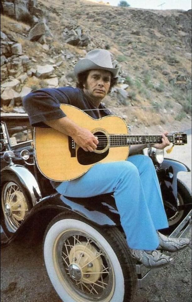 a man sitting on top of a motorcycle holding a guitar