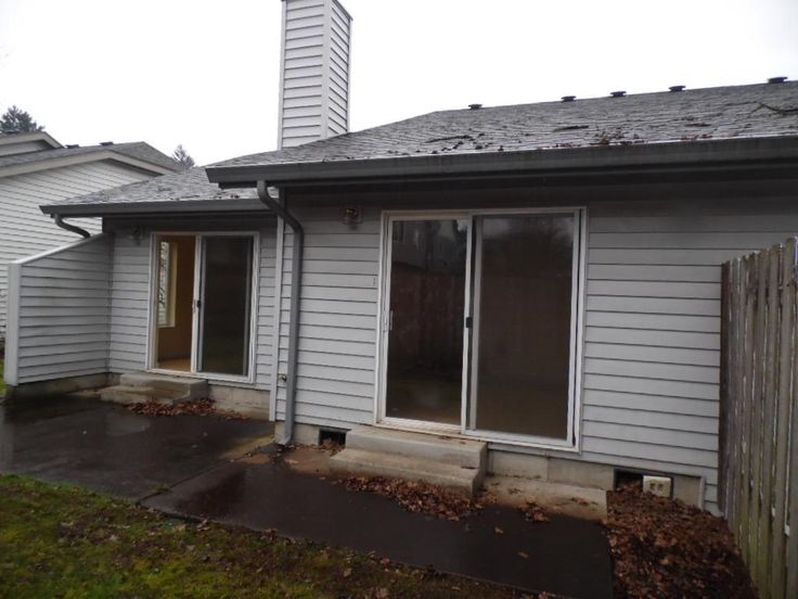 an outside view of a house that is gray and has some grass on the ground