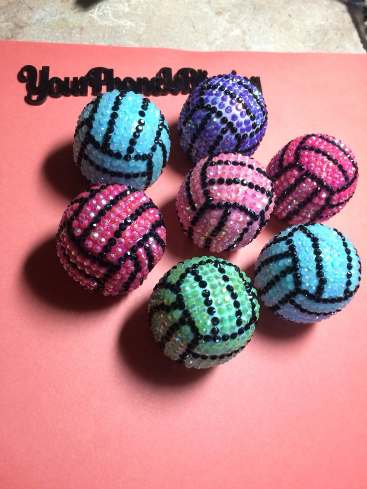 six beaded balls sitting on top of a pink surface