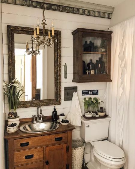 a white toilet sitting next to a bathroom sink under a mirror and a wooden cabinet