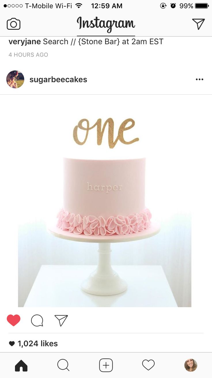 a pink and gold cake with the word'one'on it, sitting on top of a white pedestal