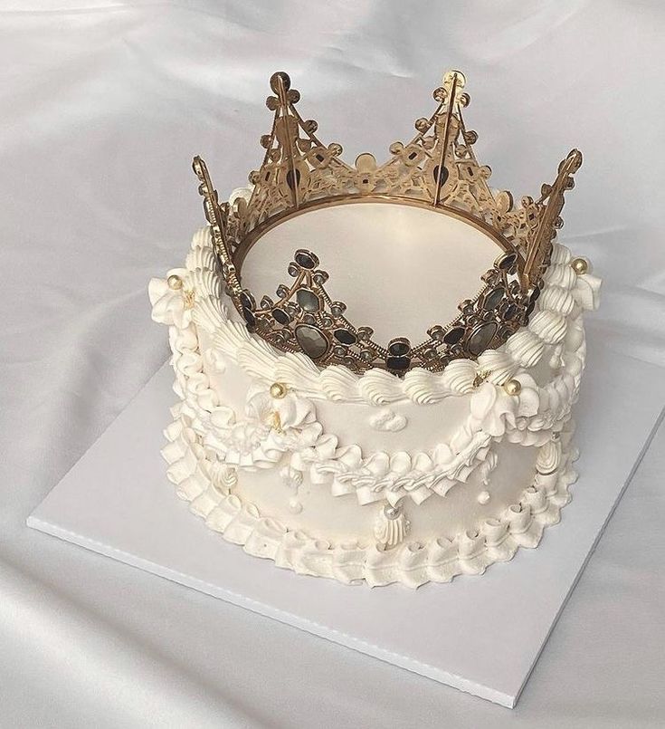 a white cake topped with a gold crown on top of a tablecloth covered sheet