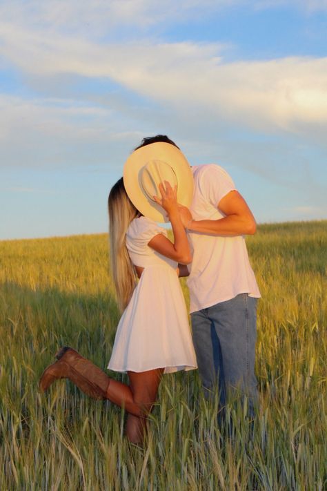 a man and woman kissing in the middle of a field with tall grass behind them