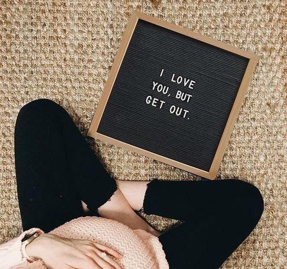 a woman laying on the floor next to a sign that says i love you, but get out