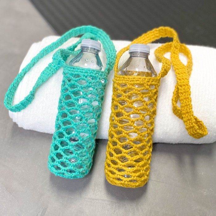 two water bottles sitting on top of a white towel covered in crocheted material