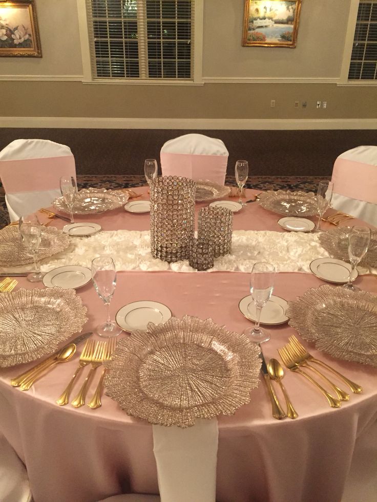 the table is set with pink linens and gold place settings