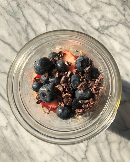 a glass bowl filled with granola and blueberries on top of a marble counter