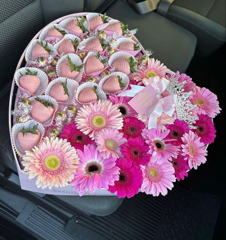 a heart shaped tray filled with pink and white flowers on top of a car seat