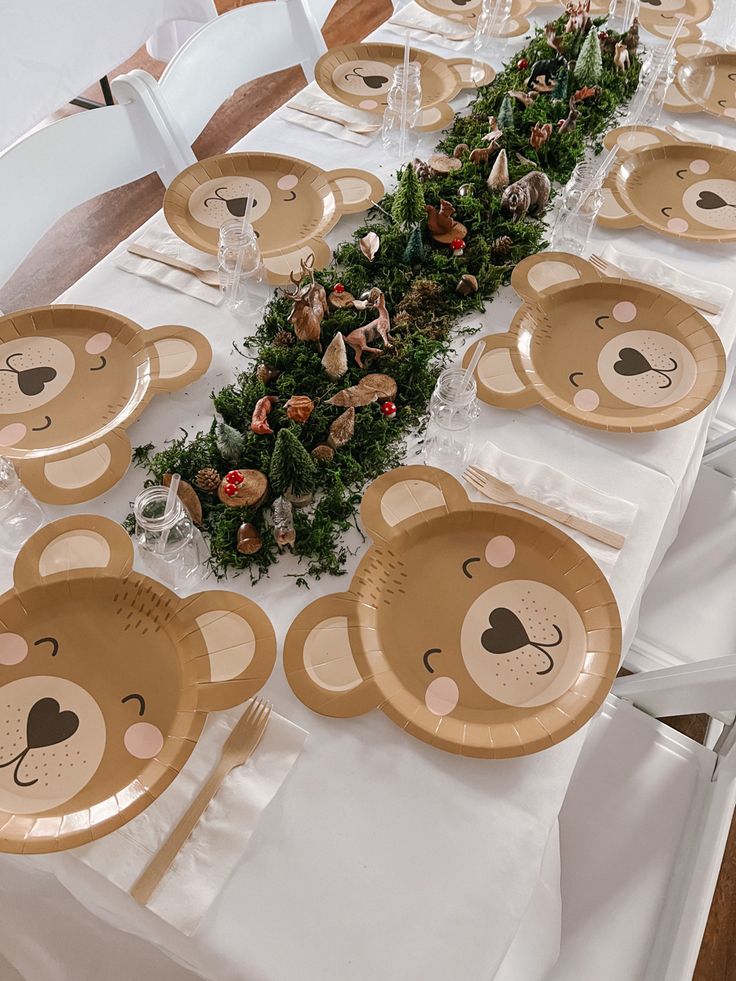 a table set up with plates and place settings for a teddy bear themed birthday party