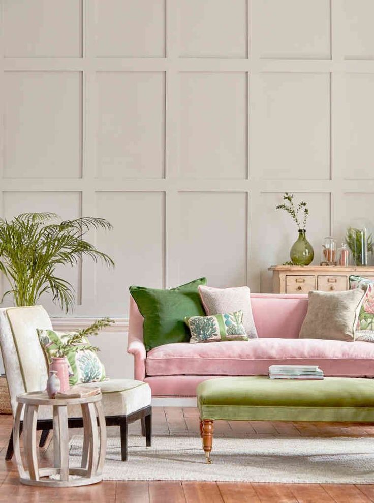 a living room with pink couches and green pillows on the back of it's sofa