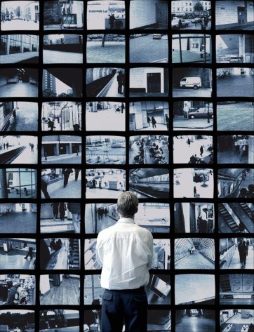 a man standing in front of a wall full of black and white pictures