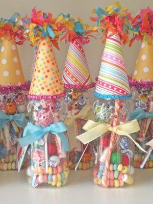 there are many candy in the bottles with hats on top and ribbons tied around them