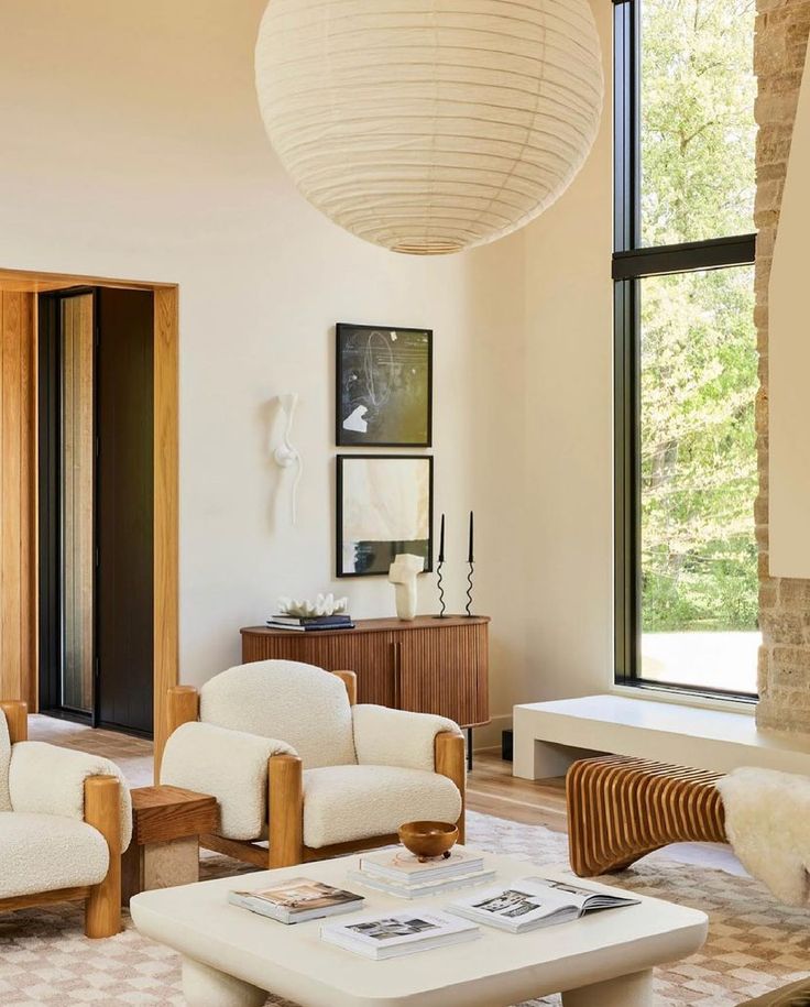 a living room with couches, chairs and tables in front of large windows that look out onto the woods