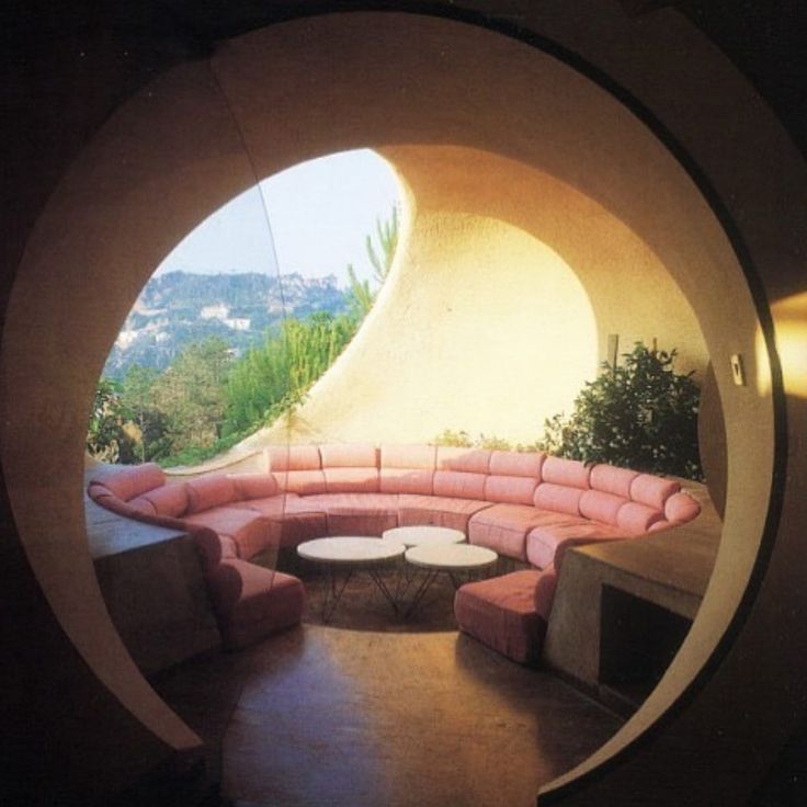 a circular couch sitting inside of a living room next to a window