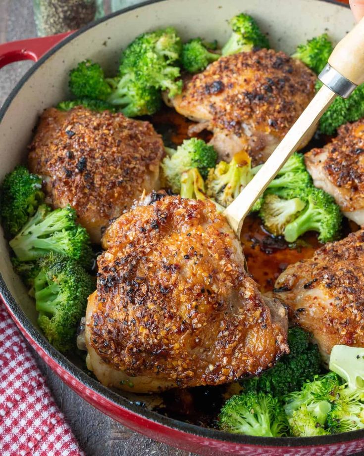 a pan filled with chicken and broccoli on top of a checkered table cloth