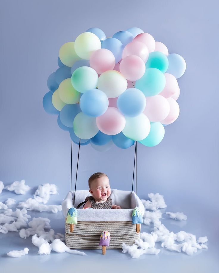 a baby in a basket with balloons floating above