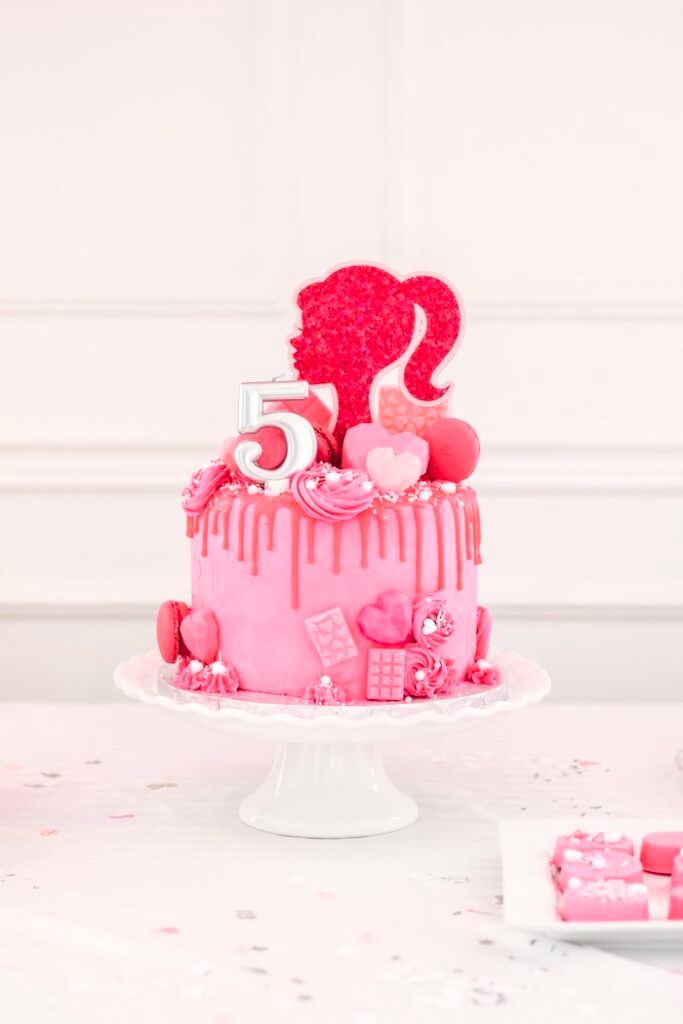 a birthday cake with pink icing and hearts on it sitting on top of a table