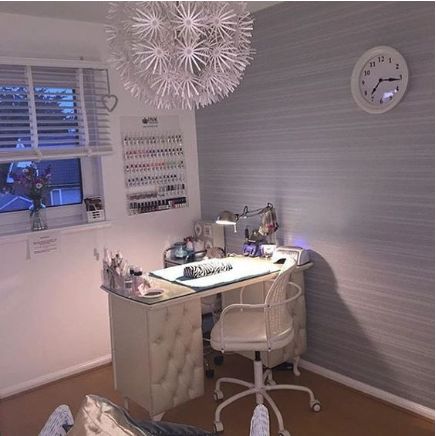 a white desk sitting under a window next to a wall mounted clock and light fixture