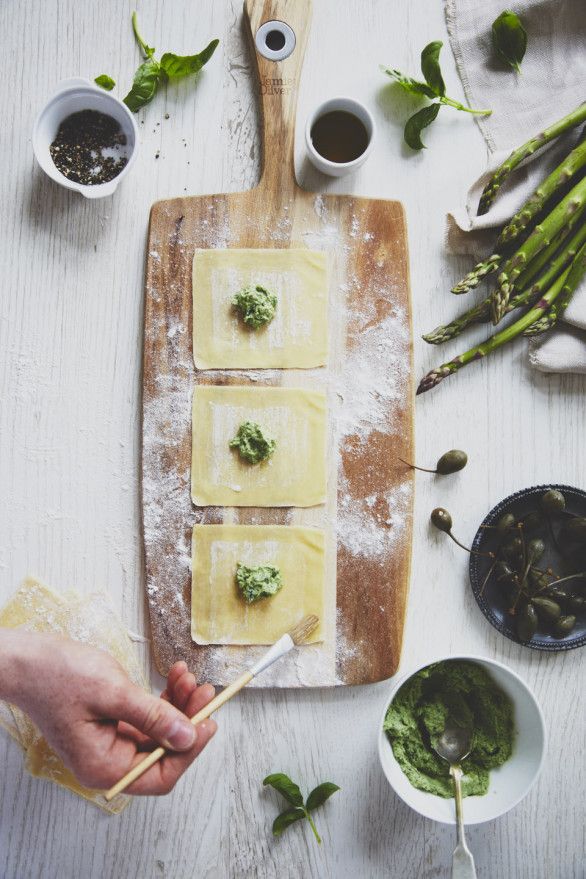 someone is making ravioli with pesto and parmesan cheese on a cutting board