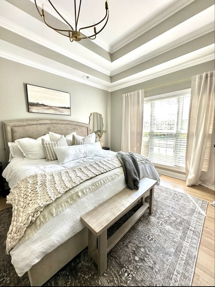 a large white bed sitting in a bedroom next to a window