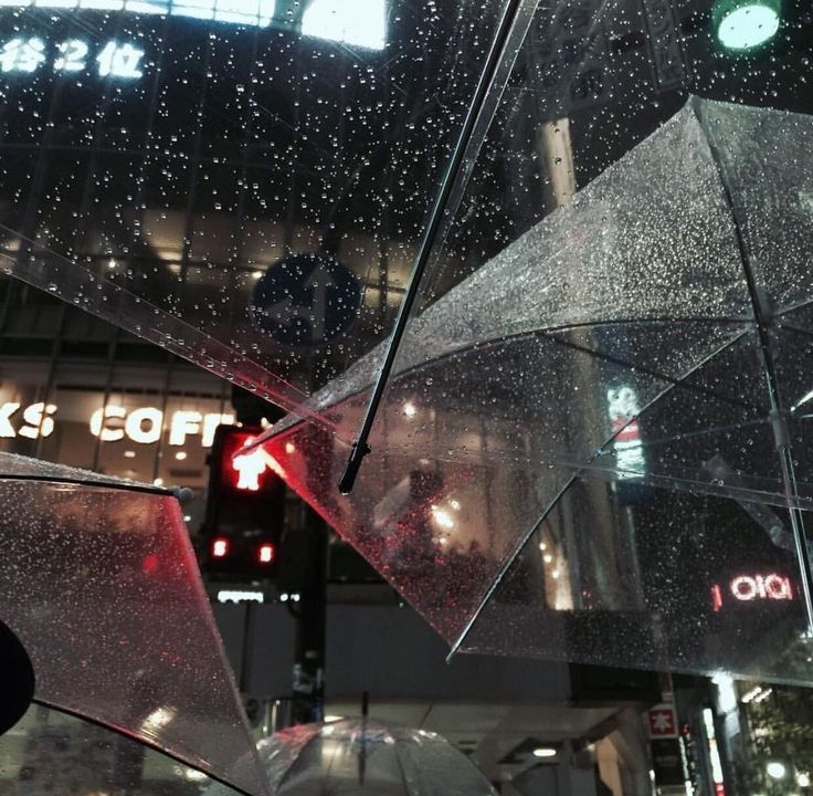 umbrellas hanging from the ceiling in a city at night with rain falling on them