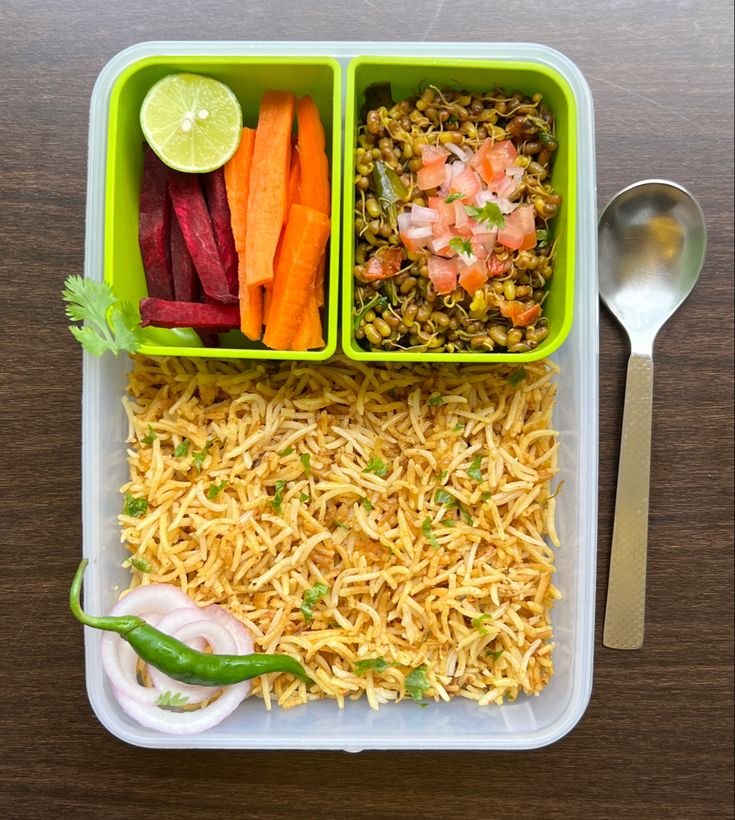 two plastic containers filled with rice, carrots and other vegetables next to a spoon